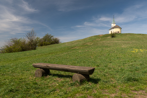 Wooden bench and chapel on hill Michelberg (Lower Austria) on a sunny day in spring