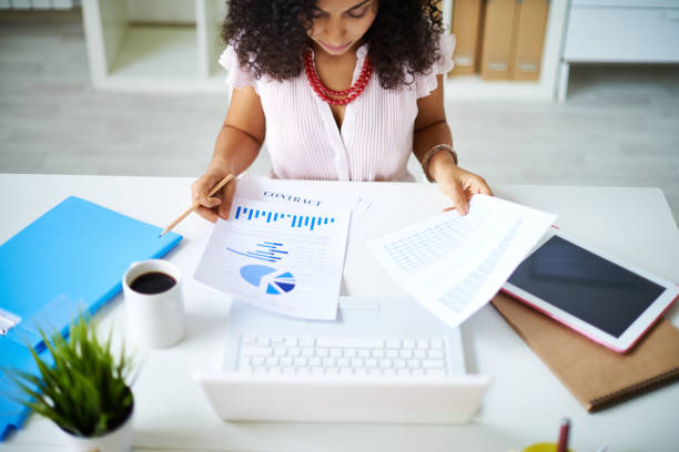Preparing project report Businesswoman examining documents sitting at office table financial report stock pictures, royalty-free photos & images