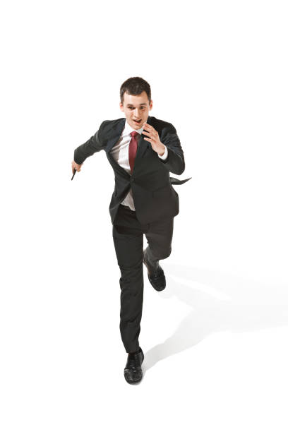 Funny cheerful businessman running with mobile phone over white studio background. happy young man in suit. Business, career, success, win concept. Victory, delight . Human facial emotions