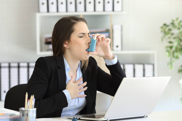 Asmathic executive inhaling with an asthma inhaler Asmathic executive having an asthma attack inhaling with a inhaler at office melancholy computer support specialist stock pictures, royalty-free photos & images