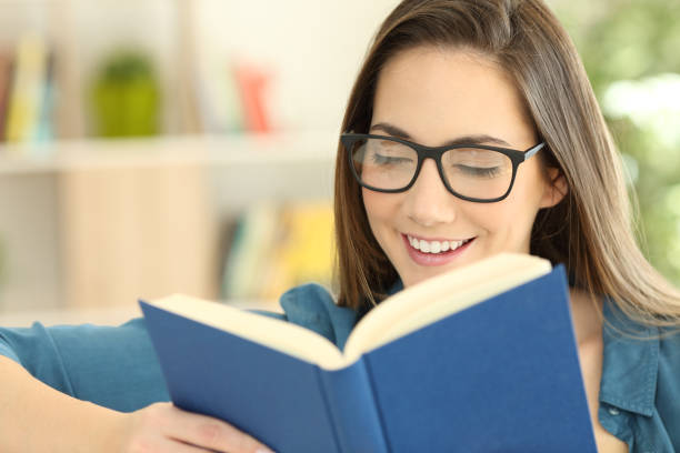 istock Girl wearing eyeglasses reading a paper book 950688374