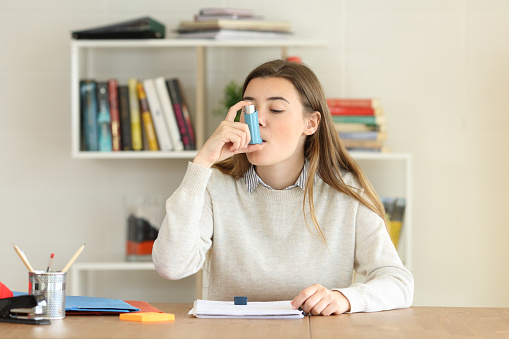 Student having an asthma attack using an asthma inhaler at home