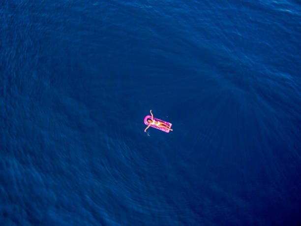 istock Woman floating on inflatable mattress on sea surface 950692908
