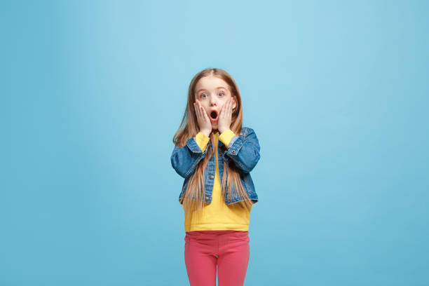 hermosa chica adolescente sorprendió aisladas en azul - child surprise little girls human face fotografías e imágenes de stock