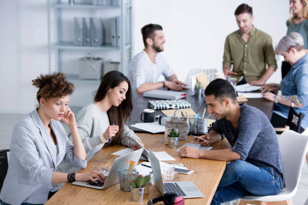 Coworkers brainstorming ideas for project Young diverse female and male coworkers brainstorming ideas for a project by a table at a start-up office real estate office stock pictures, royalty-free photos & images