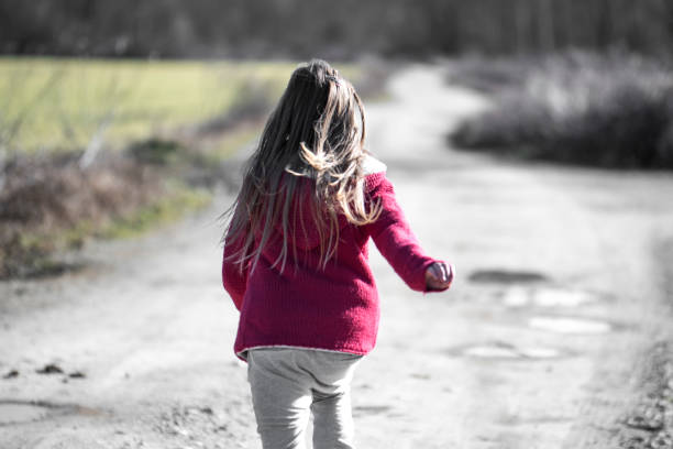 Little girl running away from camera in nature
