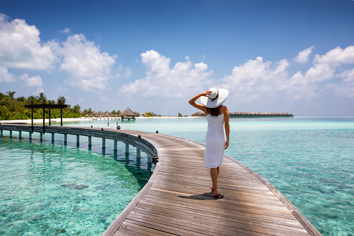 Mujer atractiva camina sobre un embarcadero de madera en las Maldivas photo