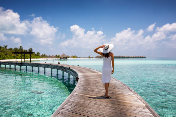attractive woman walks on a wooden jetty in the maldives - touristic resort imagens e fotografias de stock