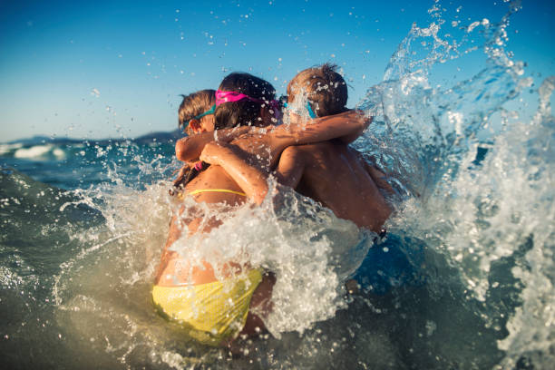 istock Kids hugging in the sea waves 950701770
