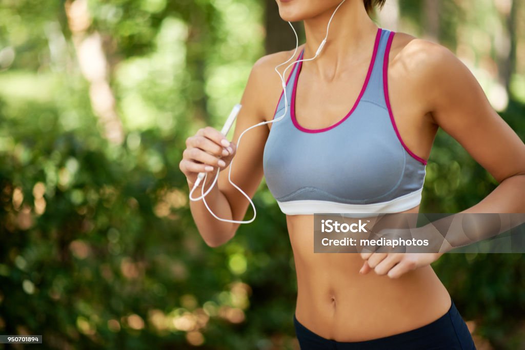 Jogging workout Slim woman jogging with personal stereo Sports Bra Stock Photo