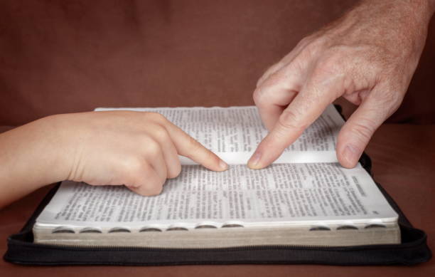 Studying the Word of God Hand of man pointing something to a child in the Bible book. Teaching a disciple from the Bible. apostle worshipper photos stock pictures, royalty-free photos & images