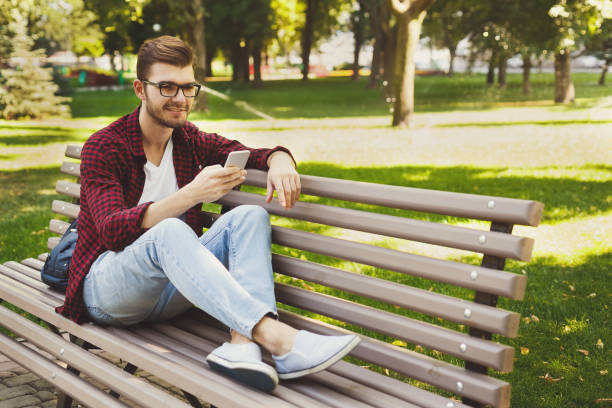 istock Handsome man sitting and using smartphone outdoors 950707546