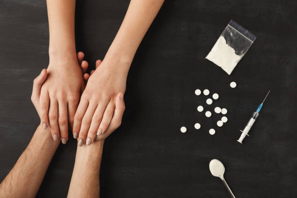 Drug addict hands on dark table Drug addict hands asking for help on dark table with cooked heroin, pills, spoon and plastic bag. Concept of addiction and International Day against Drug Abuse, top view morphine drug stock pictures, royalty-free photos & images