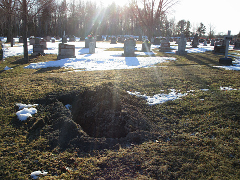 rays of sunlight on a partially open grave in a cemetery