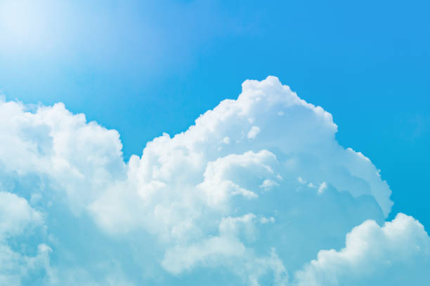 istock White cumulus fluffy clouds against a bright blue sky and sun 950718516