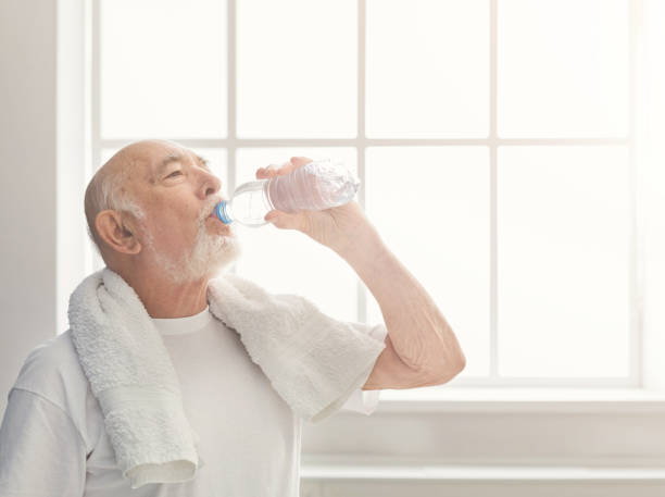 istock Thirsty senior man drinking water from bottle 950718610