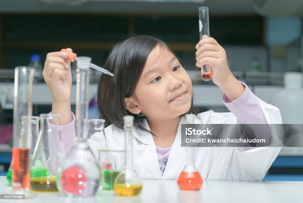 Happy little scientist making experiment Happy little scientist in lab coat making experiment with test tube in chemical laboratory, science and education concept Child Stock Photo