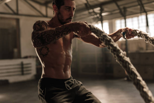 istock Athlete working out with battle ropes at gym 950732426