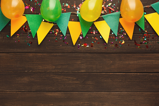 Colorful paper flags garland and baloons on rustic wood. Birthday party decoration background, top view, copy space. Mockup for greeting card