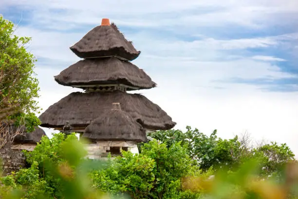 Pura Luhur Uluwatu Temple, Bali Indonesia on cliffs above blue tropical sea with green landscape. Nusa Dua
