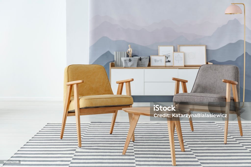 Yellow and grey living room Yellow and grey armchair next to wooden table on striped carpet in cozy living room interior Living Room Stock Photo