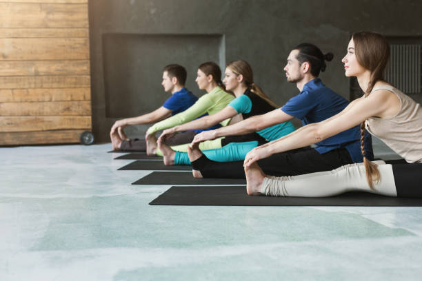 istock Young women and men in yoga class, doing stretching exercises 950746906