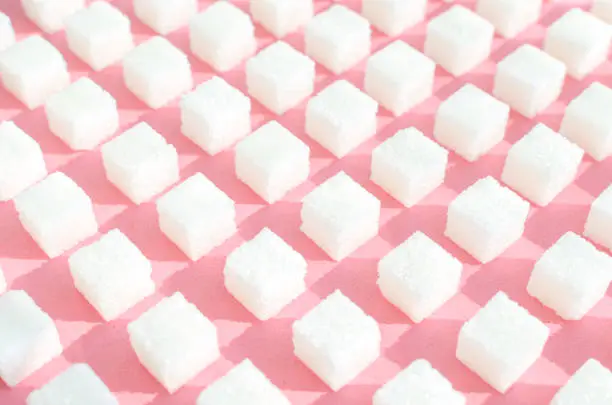 Photo of Refined sugar on pink background.Cubes of sweet and white sugar in geometricshape. Hard shadows.