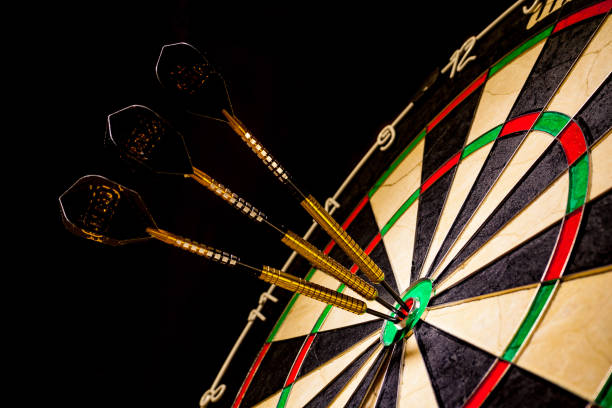 istock Sisal dartboard with three darts in a bullseye on a black background 950762936