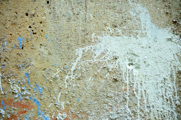 High resolution old weathered polychrome concrete wall detail, coated with multiple layers of various paints, applied through the years randomly one on top of the other, slowly cracking and peeling off, run down by the elements, high resolution grunge background texture stock photo.