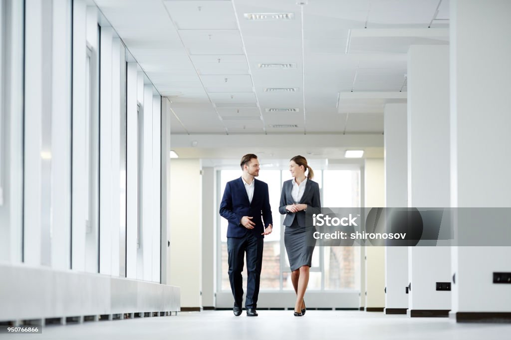 Manager with his secretary Confident business colleagues walking down in office building and talking Walking Stock Photo