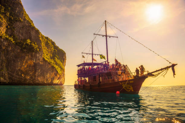 Boat in pirate style with many tourists at Maya Bay in Thailand Koh Phi Phi Lee, Thailand - April 3, 2018 : A big boat in pirate style with many tourists enjoy a sunset at Maya Bay on Phi Phi island. phuket beach party stock pictures, royalty-free photos & images