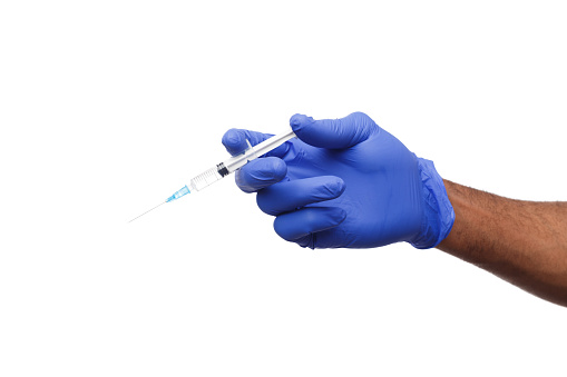 Black male hand in blue gloves holding a plastic syring with liquid for injection isolated on white background. Health care, treatment concept
