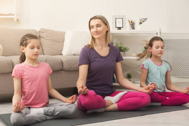 istock Young woman and daughters doing yoga exercise at home 950779176