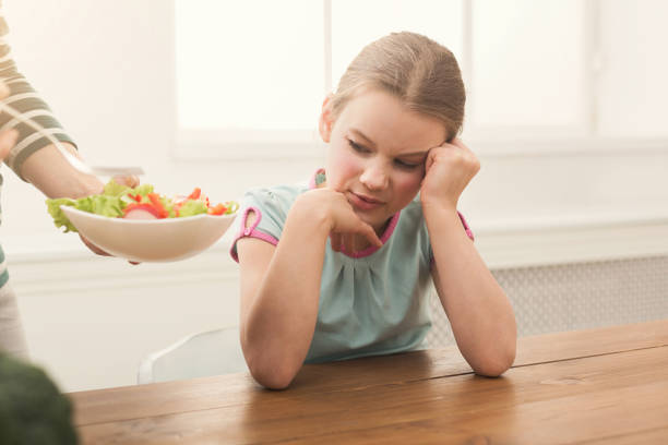 istock Woman offering her daughter salad but girl refusing 950779332