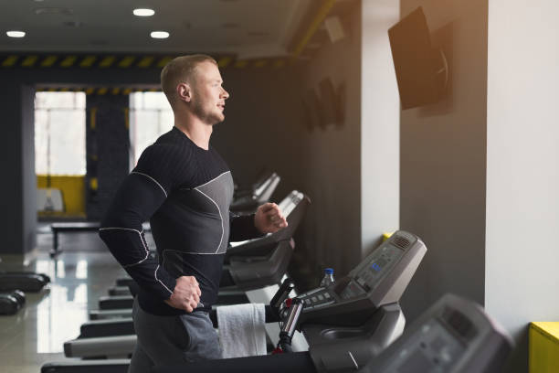 istock Young man in gym running on treadmill 950783180