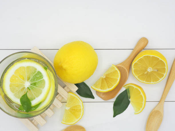 istock Fresh lemon in water and lemon slice on white wood background 950783608