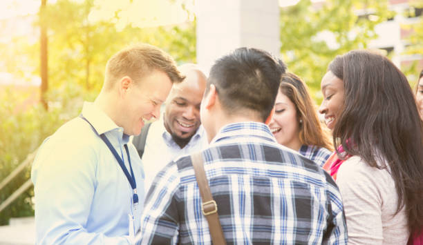 College recruiter or tour guide shows campus to potential students.  Multi-ethnic group of young adults.