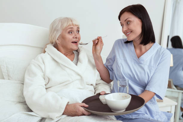 istock Joyful caregiver giving breakfast to elder woman 950787932