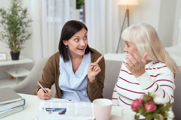 istock Merry elder woman and caregiver solving crossword 950791938