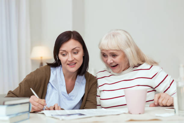 istock Active elder woman and caregiver viewing newspaper 950791978