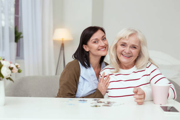 istock Appealing elder woman and caregiver compiling puzzle 950792460