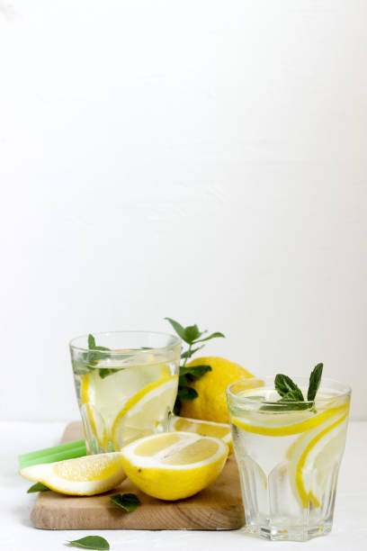 istock Lemonade with lemon slices, mint and ice and lemons on a light concrete background. Rustic style. 950792560