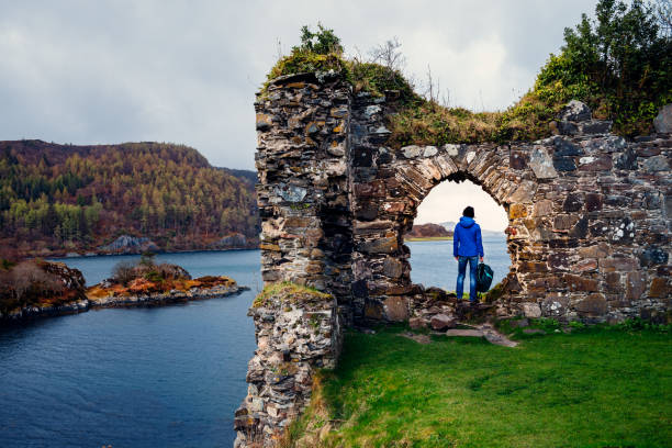 Female tourist at the ruins of Strome Castle on the shores of Loch Carron in the Wester Ross region of Scotland.