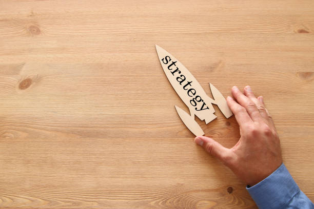 istock man's hand holding rocket with word - strategy - over wooden background. 950806580