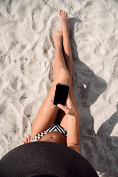 istock Girl using mobile phone app texting sms or browsing on online social media. Summer beach vacation. 950816244