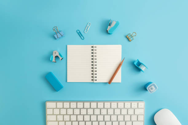 istock Flat lay, top view office table desk. Workspace with blank note book, keyboard, Blue office supplies and coffee cup on white background. 950816362
