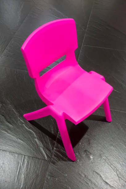 istock Pink plastic chair for kid on black floor background 950825972