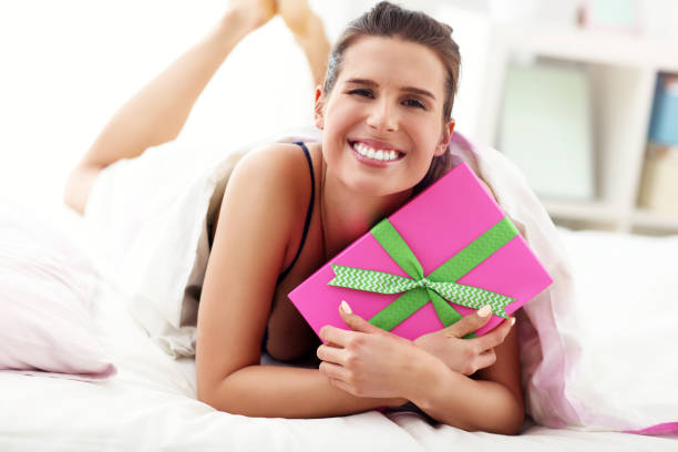 istock Young woman unpacking a surprise present in bed 950826652