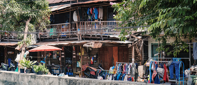 Bangkok, Thailand - March 2, 2018: Panoramic view of old Thai poor huts on the banks of the Chao Phraya River seen from Saphan Phut Road.
