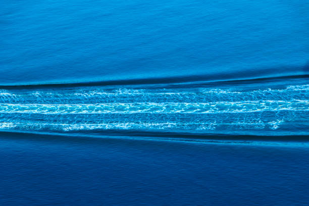 Horizontal minimalist image of speedboat wake with varying blues and lavender hues.
